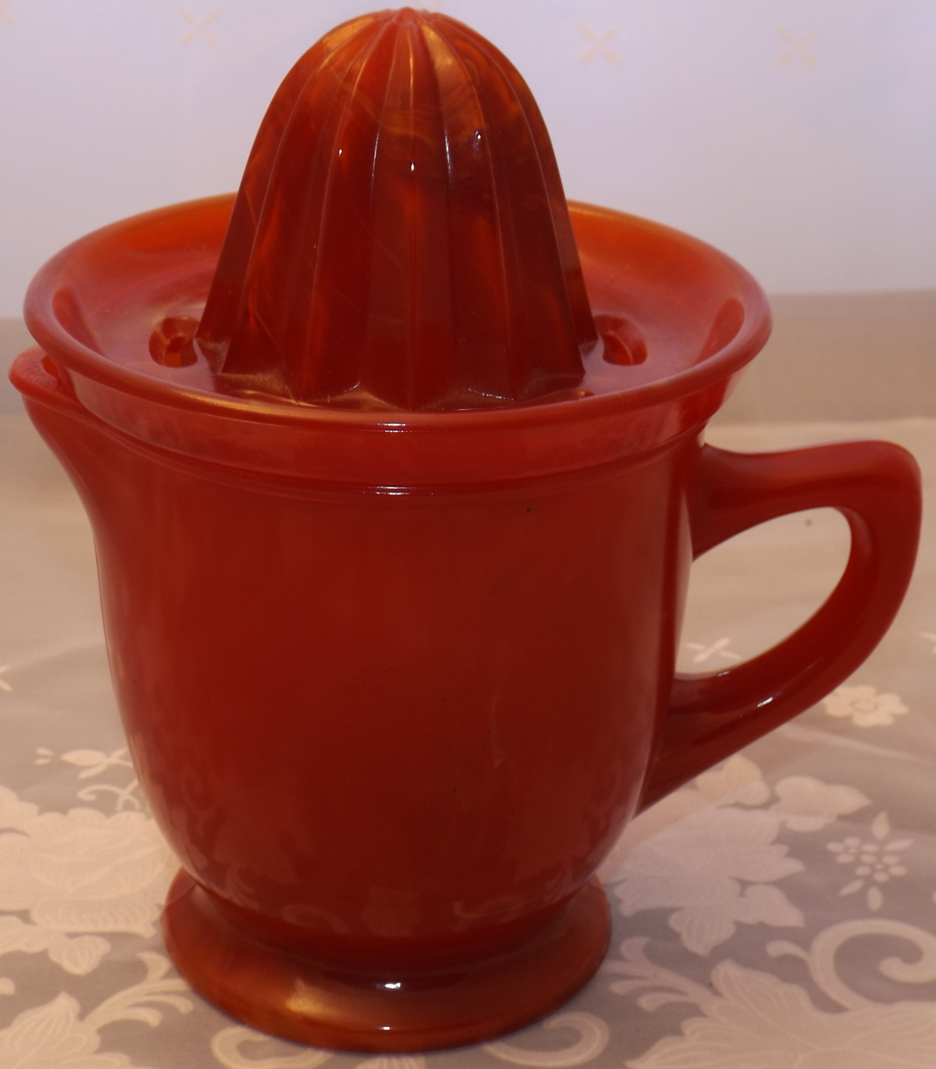 Red slag glass juicer embossed with a lemon an a orange
