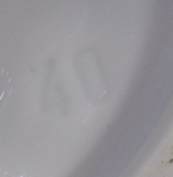 Impressed mark on a Small white saucer offset curved tab handle juicer