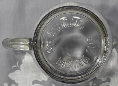 The embossed "MEASURING MIXING CUP" on the base of a 2 piece clear glass juicer