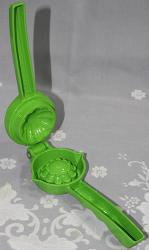 An open green die cast aluminium hand held lime squeezer