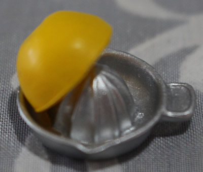 A miniature plastic juicer with offset tab handle decorated with an orange half