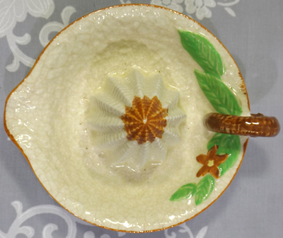 Beige loop handle juicer with tan flower and green leaves top view