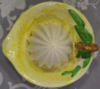 Yellow loop handle juicer with white flower and green leaves top view