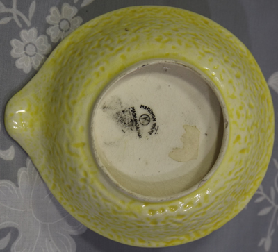 Base of yellow loop handle juicer with white flower and green leaves
