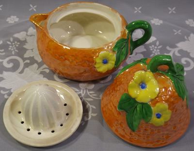 3 pieces of an orange with yellow flowers pear shape juicer
