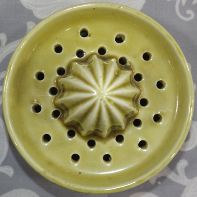 Reamer for a pineapples on an olive green pitcher with green fruit juicer