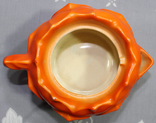Top view of a Manto Ware basemark on a ceramic flower shaped orange ceramic juicer jug