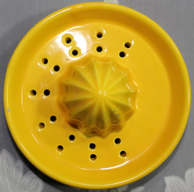 The 2 parts of a 4 orange flowers on a white and yellow juicer