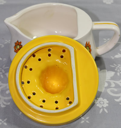 The 2 parts of a 4 orange flowers on a white and yellow juicer