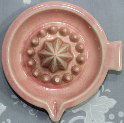 Top view of a 1 piece pink saucer shape ceramic juicer