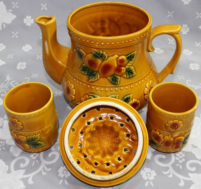 The matching tumblers for a tan teapot shape juicer with relief fruit and flowers