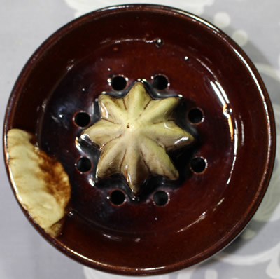The reamer for a dark brown with areas of lighter brown drip glaze juicer 