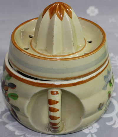 The handle on a pale and dark crimson flowers on beige ceramic juicer
