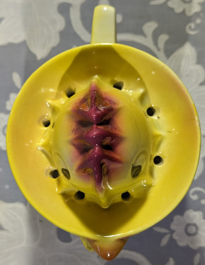 Top view of a Goebel yellow chicken juicer with maroon trim