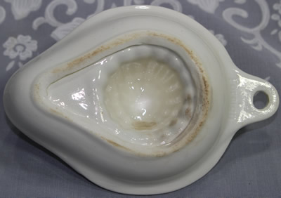 The open base of a white German ceramic strainer juicer