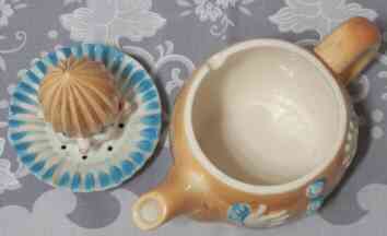 The 2 parts of a tan clown with blue ruffles ceramic juicer