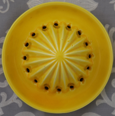 Reamer for a yellow lemon with brown handle ceramic juicer