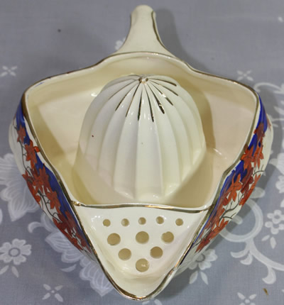 The pouring spout on a red flowers and blue trim on white Japanese ceramic juicer