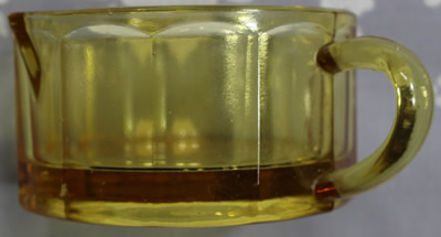 The panels on an amber glass 2 piece juicer with offset loop handle