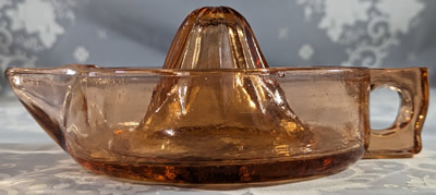 Side view of a large reproduction amber glass juicer 