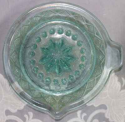 Top view of a diamond pattern aqua blue green glass saucer juicer