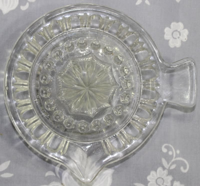 The top view of a fish tail shape handle clear glass saucer juicer