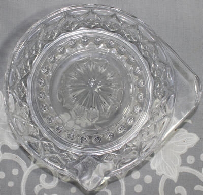 Top view of a diamond pattern on larger tab handle clear glass saucer juicer 