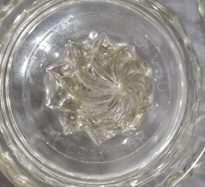 The embossed base of a U.S. Glass Co. clear glass spiral cone juicer