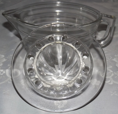 Under the top of a large clear 2 piece banded glass juicer