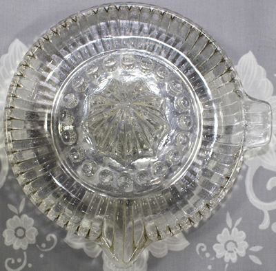 A clear glass juicer with ribbed tab handle top view