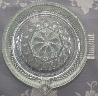 Top view of a ribbed tab handle clear glass saucer juicer