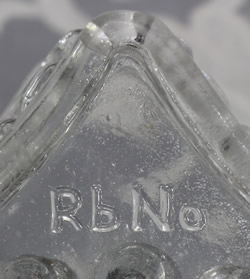 The embossing of "RbNo" on a trapizoidal shape clear glass juicer