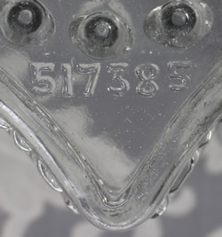 The embossing of "517385" on a trapizoidal shape clear glass juicer