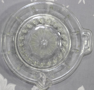 Top view of an alternating 4 horizontal lines and plain panels clear glass sauce shape juicer