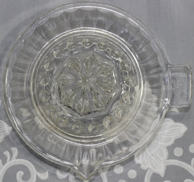 Top view of a crossed hammer and sword clear glass saucer shape juicer