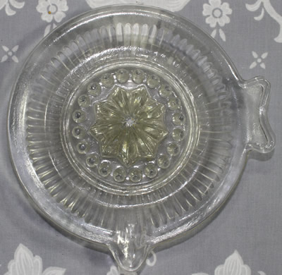 Top view of a straight flutes fish tail shape handle clear glass juicer 