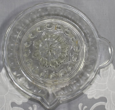 Top view of a circular tab handle clear glass saucer juicer