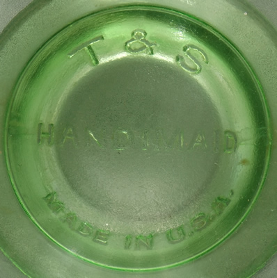 The embossed base of a Hazel Atlas T & S HANDIMAID green uranium glass juicer