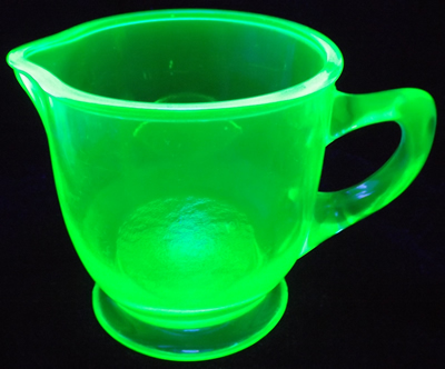 Uranium green glass juicer embossed with a lemon and an orange under UV light