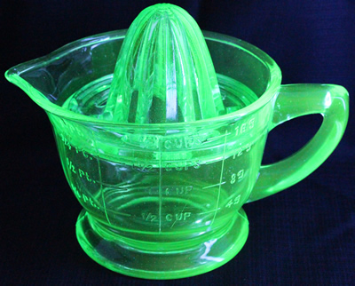 A turquoise 2 piece glass US Glass Co. juicer under UV light