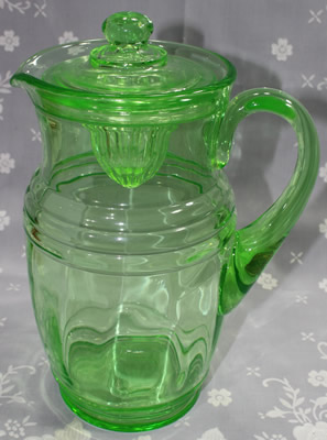 A closed large green glass jug juicer with lid 