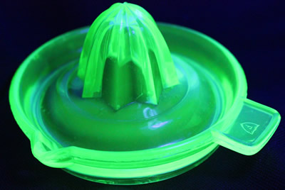 A Federal Glass green glass offset tab handle juicer under UV light