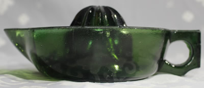 Side view of a square handle emerald green glass juicer