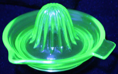 A green Jeannette Glass large saucer juicer under UV light