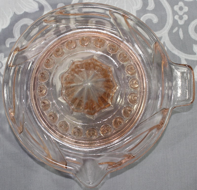Top view of an interlocking swirls on a pink glass juicer 