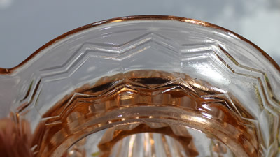 The zig-zag pattern on a pink glass saucer shape juicer 
