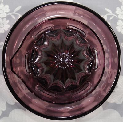 Purple glass juicer embossed with a lemon and an orange reamer