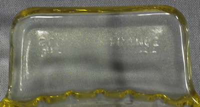Embossed "arc FRANCE" on the tab handle of a yellow and clear glass juicer 