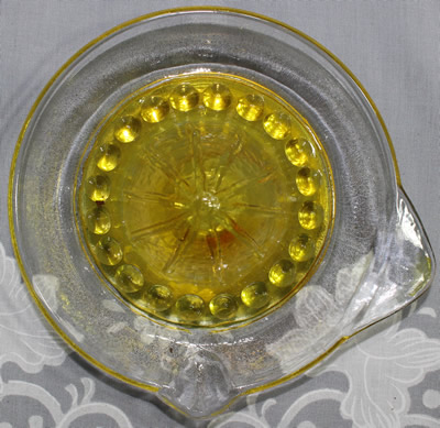 Top view of a yellow and clear glass 'Margarita Set' saucer shape juicer 