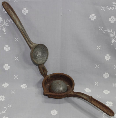 An open embossed "L F & C" iron squeezer with feet 